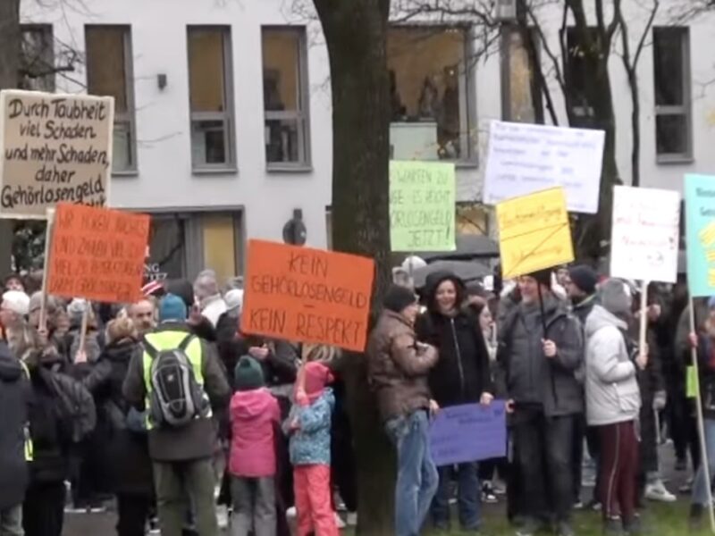 Demonstranten protestieren bei der Aktion Gehörlosengeld mit Plakaten.